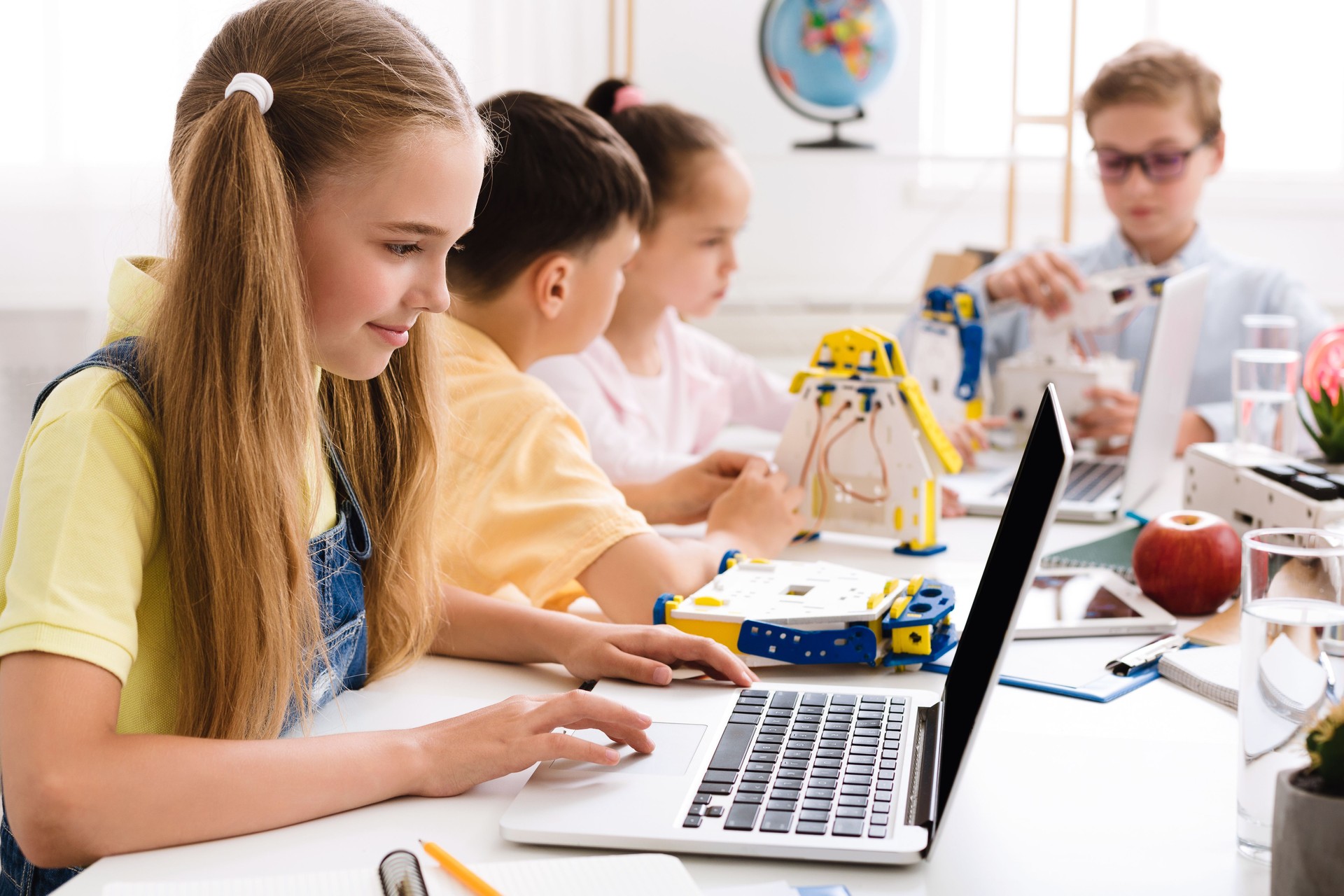 Children Engaged in STEM Activities While Working on Laptops in a Bright Classroom