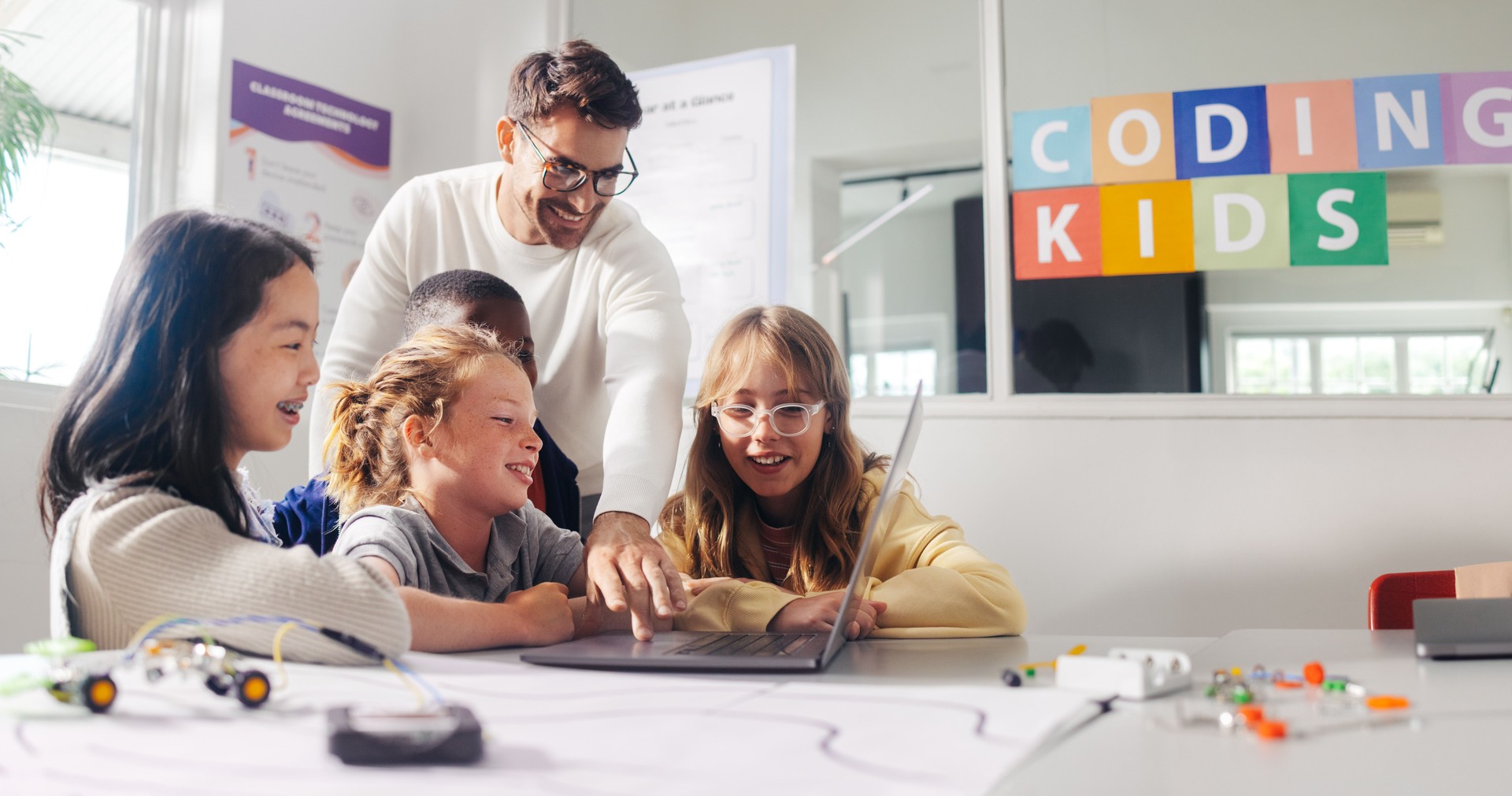 Elementary school coding: Teacher demonstrates mechanical robot programming to young students